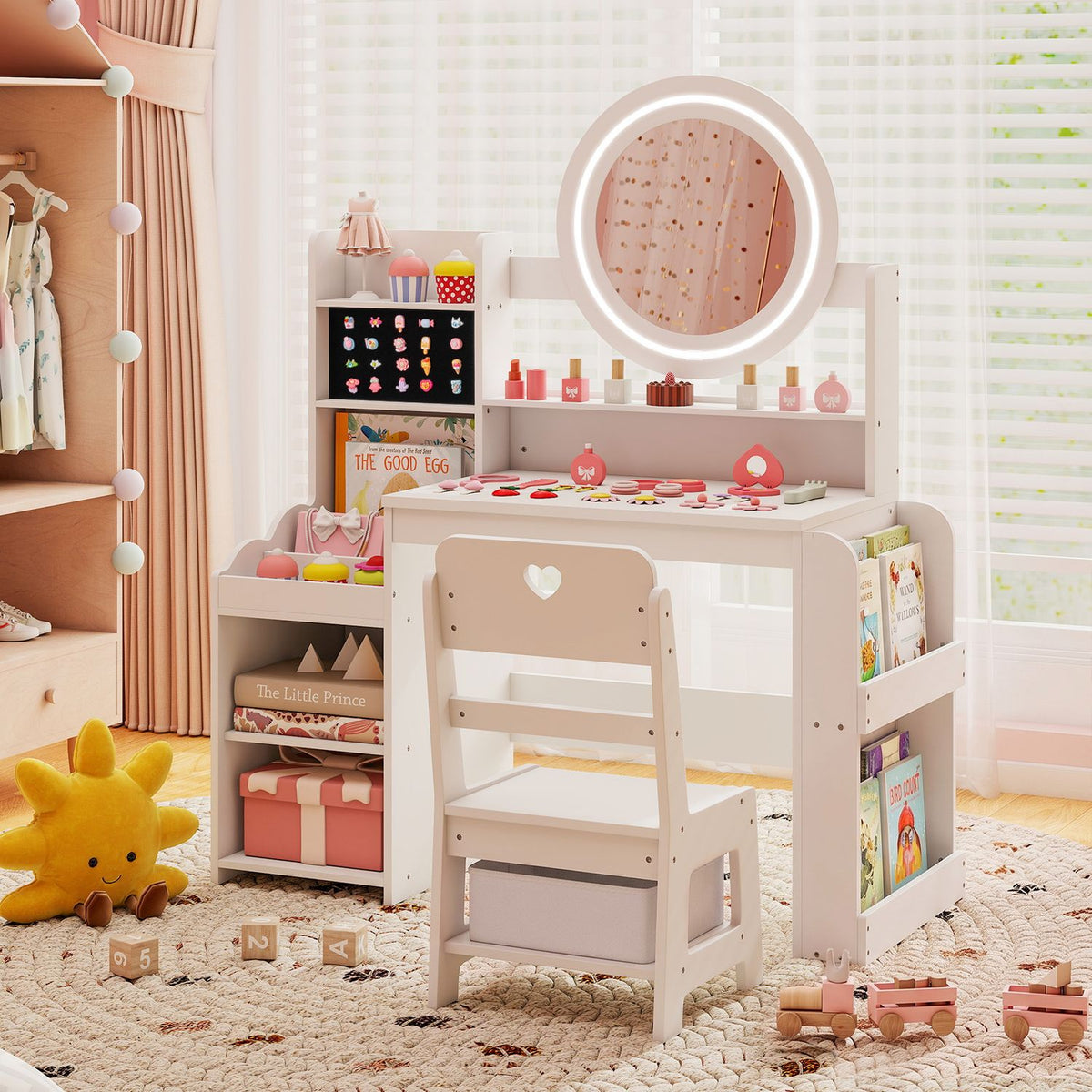 A pale pink vanity with a round lighted mirror, shelving, and a matching chair in a child’s bedroom.