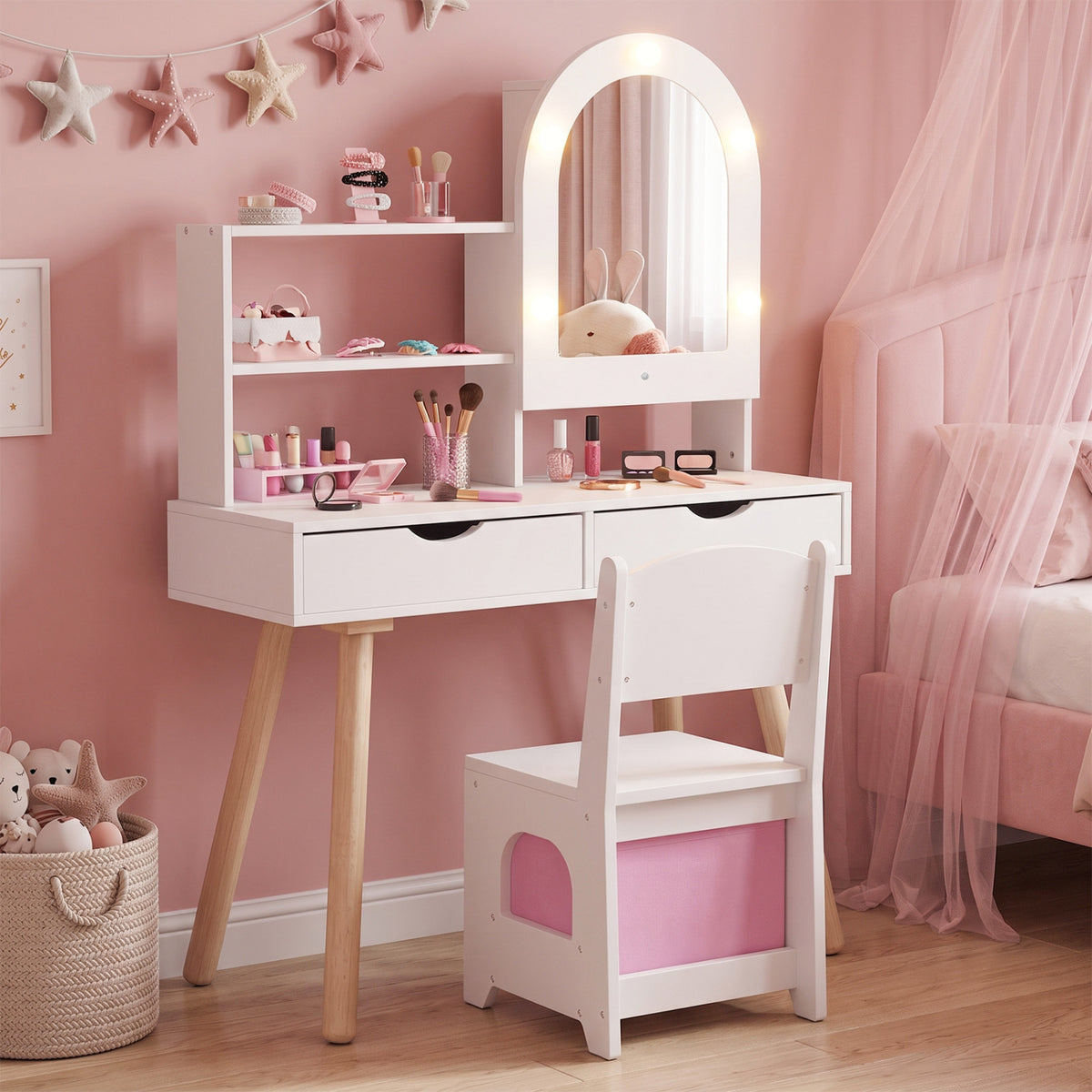 White vanity set with an arched illuminated mirror, shelves, chair, and pink storage in a pink bedroom.