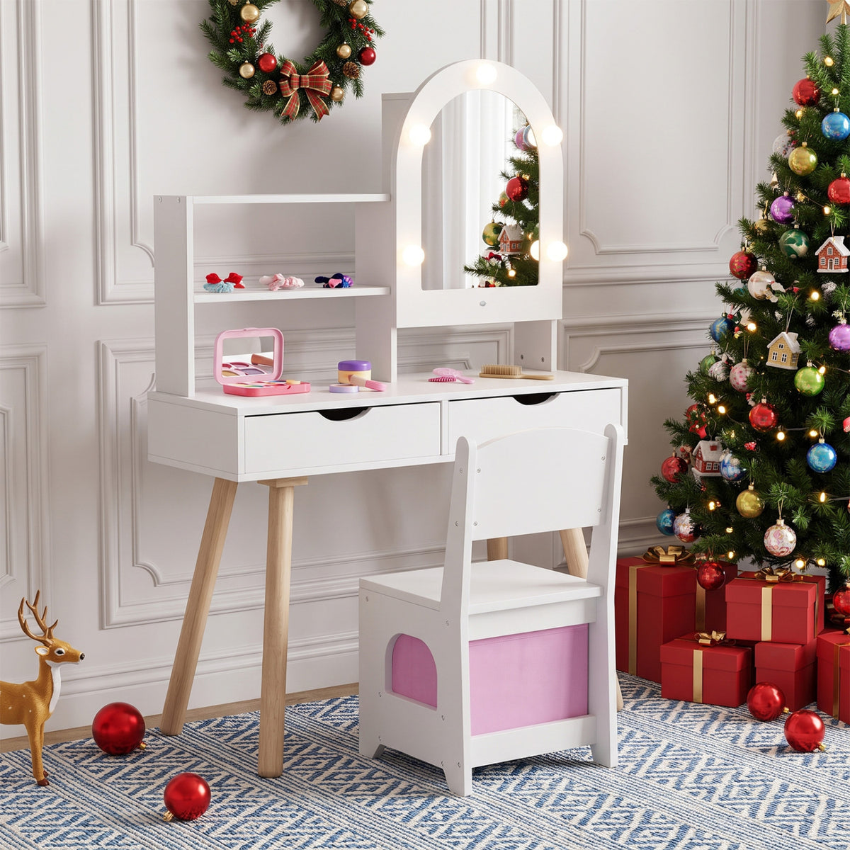 White vanity with an arched, bulb-lit mirror and pink chair, staged beside decorated Christmas trees.