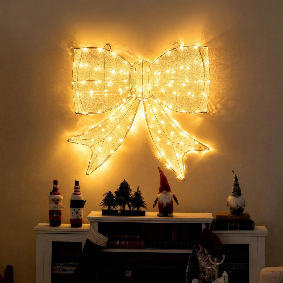Glowing golden bow mounted above a fireplace, with holiday figurines arranged on the mantel.