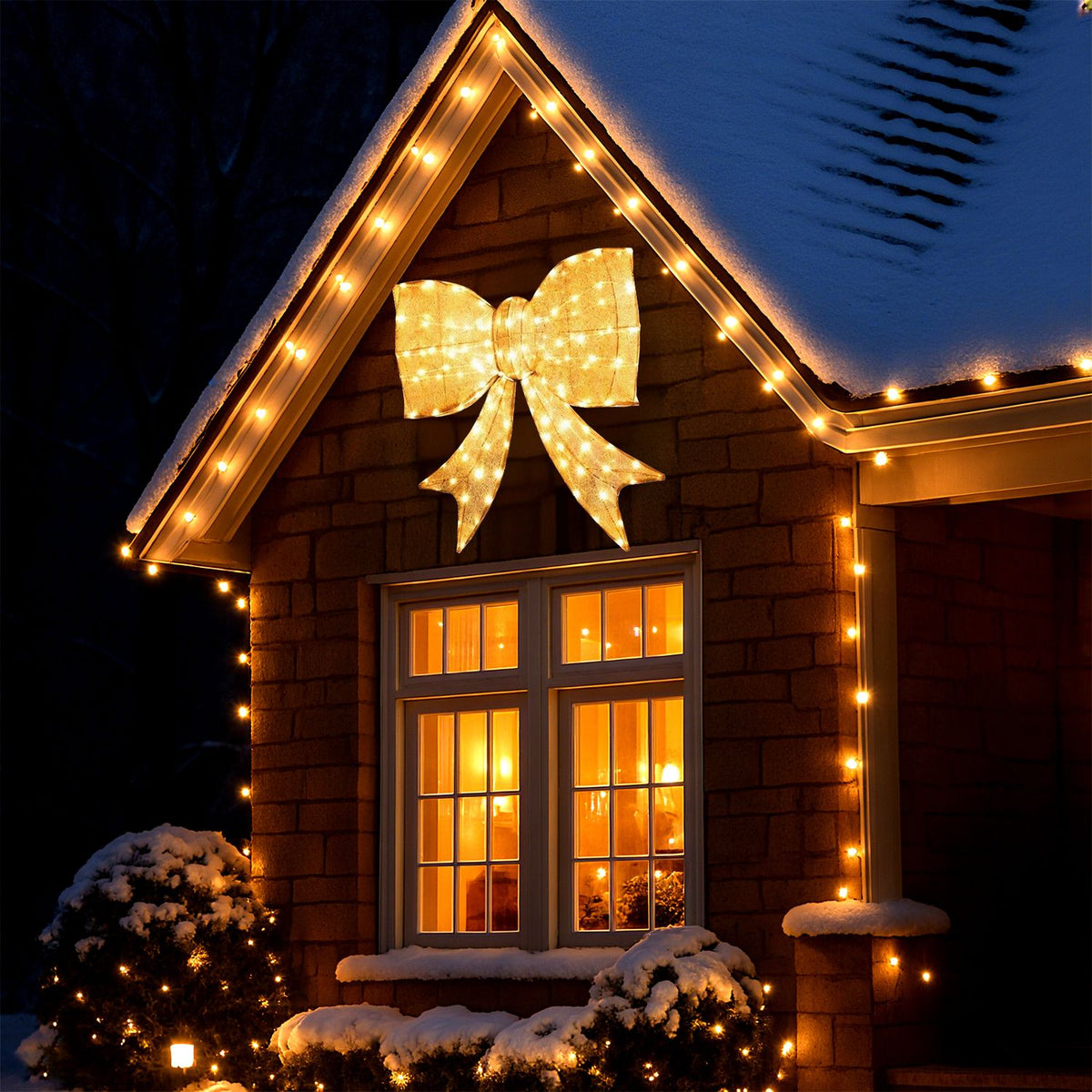 A glowing golden bow hangs above a snowy house window, with warm lights outlining the roof.