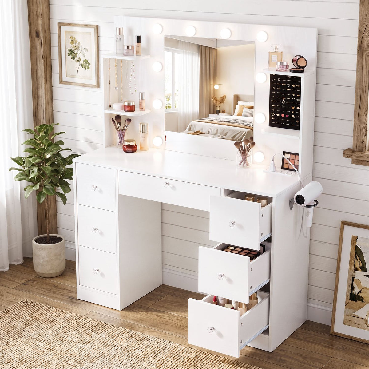 White vanity with illuminated mirror, makeup shelves, side-mounted hair dryer, and several open drawers.