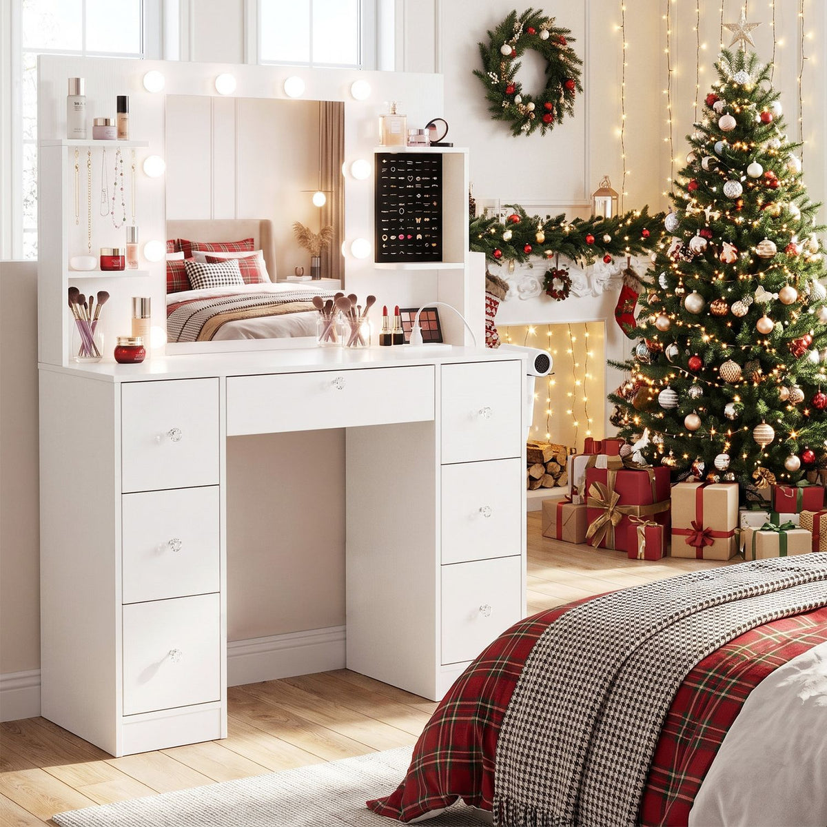 White vanity with lit mirror and closed drawers in a festive bedroom beside a decorated Christmas tree.