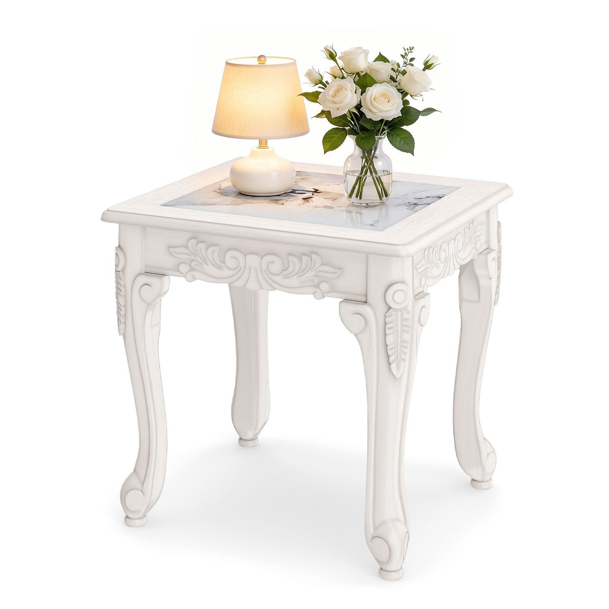 White carved coffee table styled with a lamp and flowers on its glass top