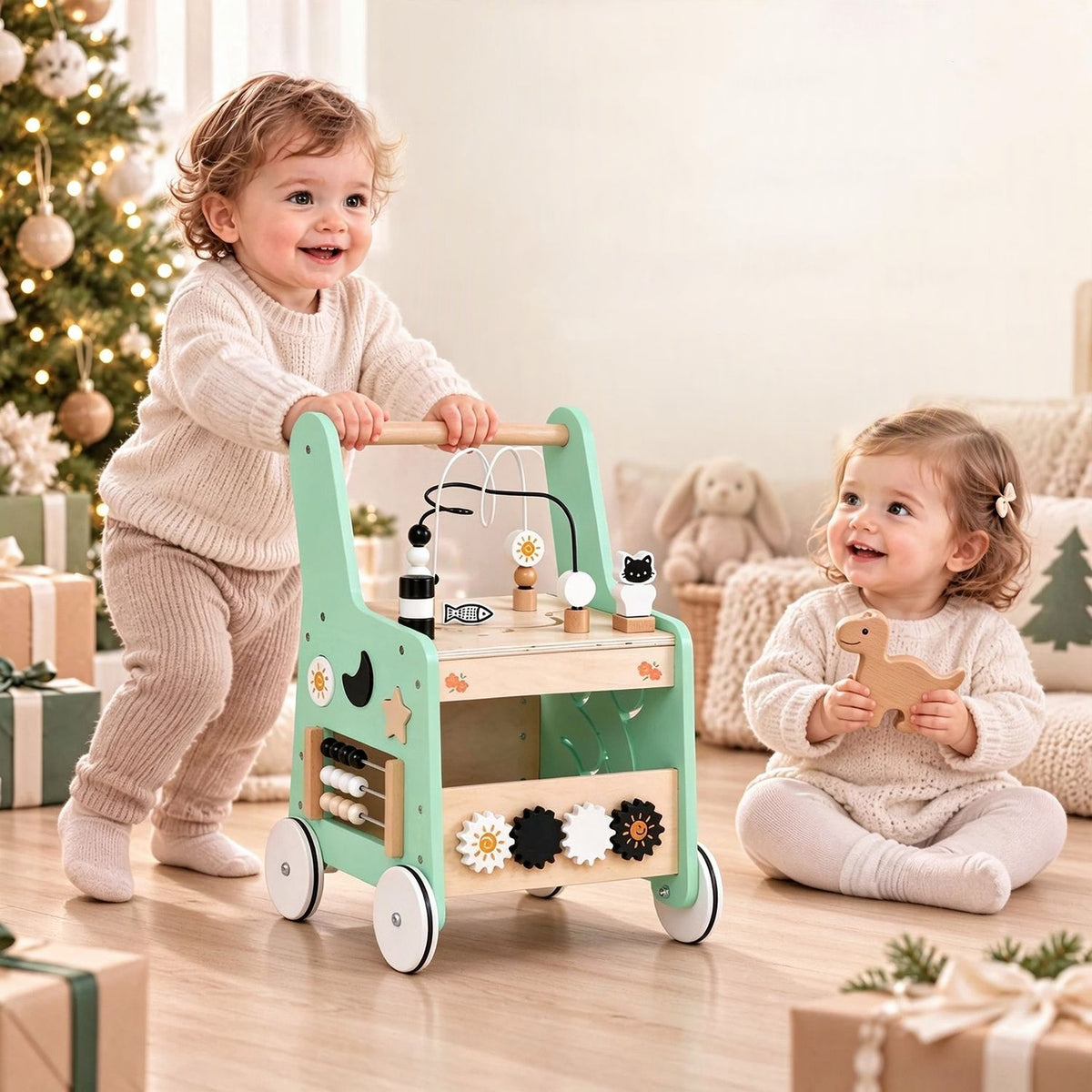 A toddler stands behind the mint-green activity walker while another child sits beside it.