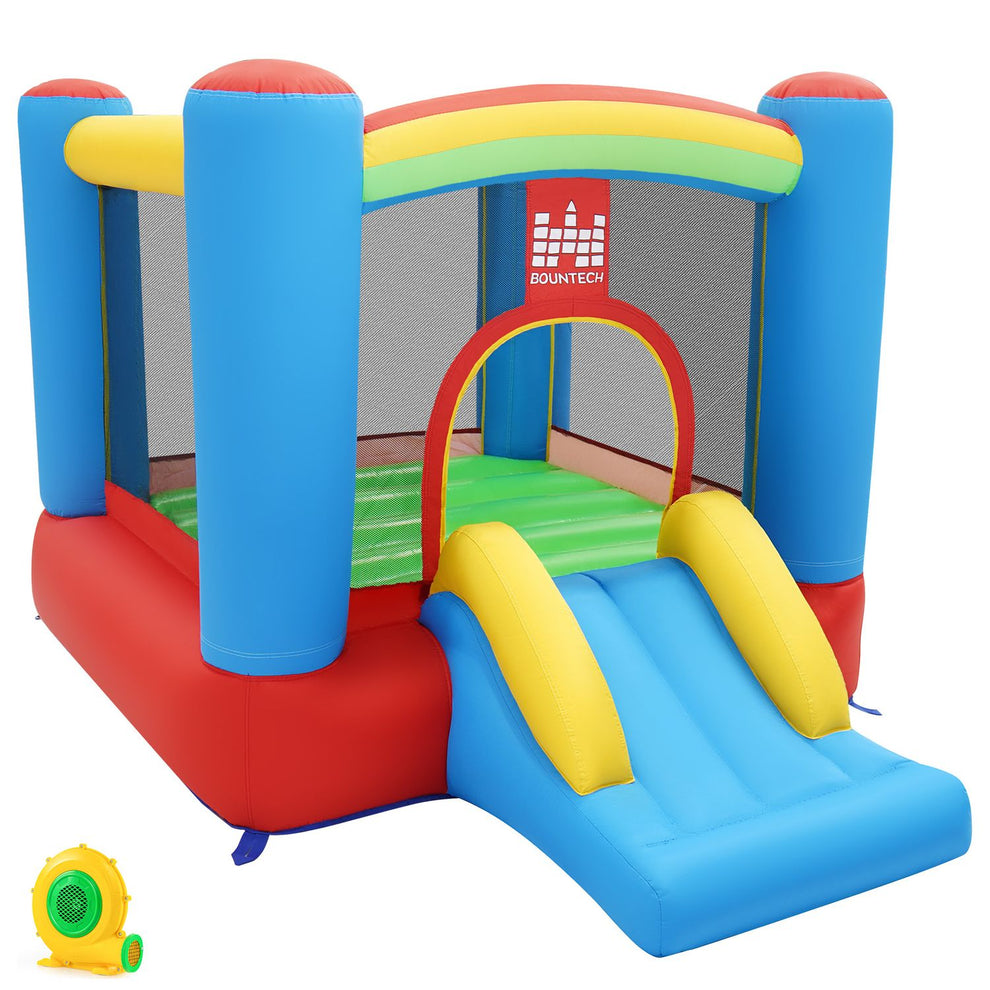 Colorful inflatable bounce house with a front slide and a small blower beside it.
