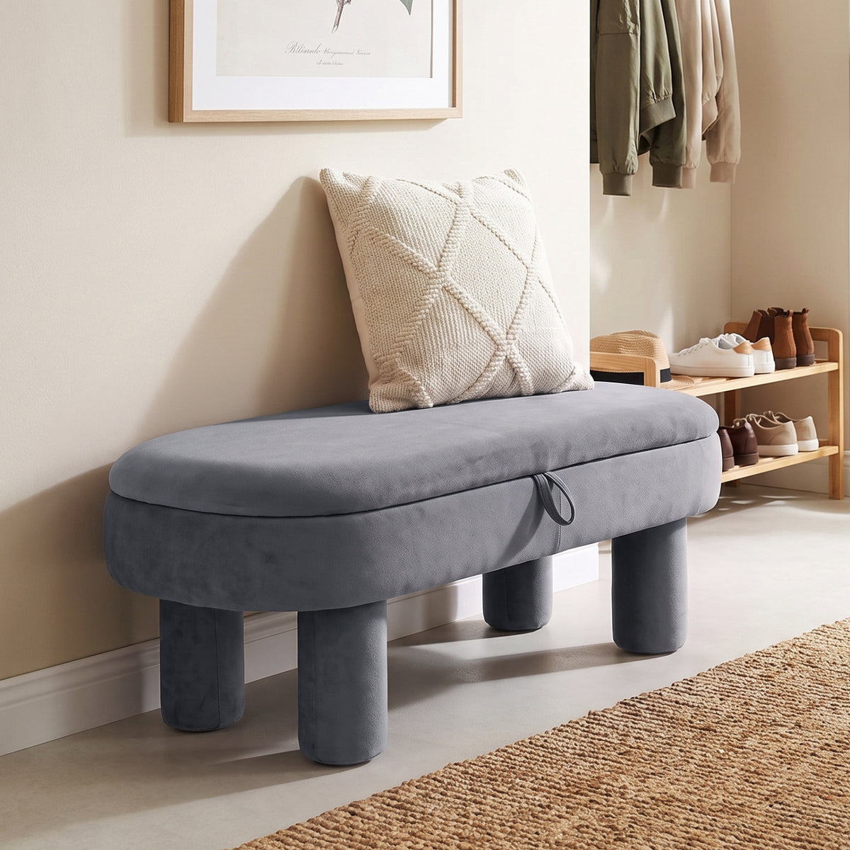 Gray oval storage ottoman beside a shoe rack in a bright entryway, with a cushion resting against the wall.
