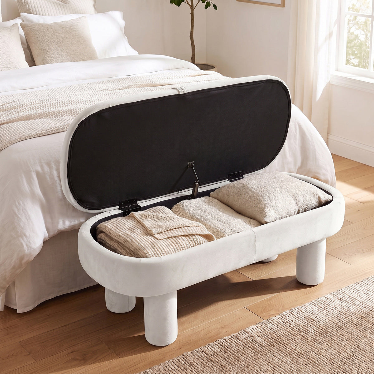The bench lid is raised to show folded blankets and pillows inside its storage compartment.