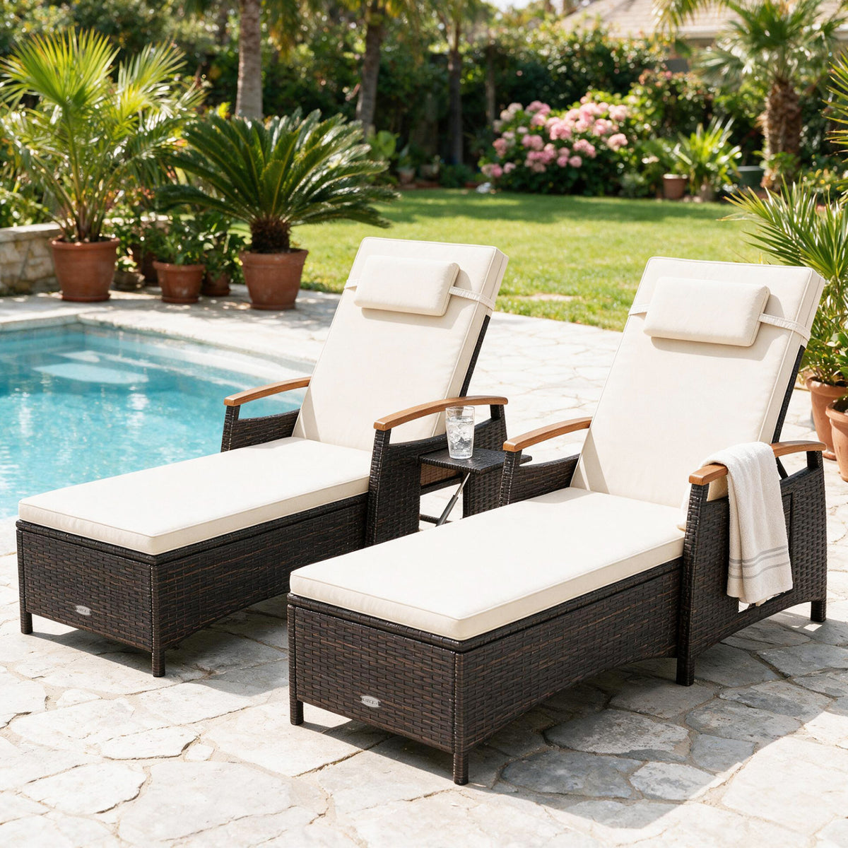 Two matching cushioned chaise lounges beside a pool, with a towel draped over one arm.