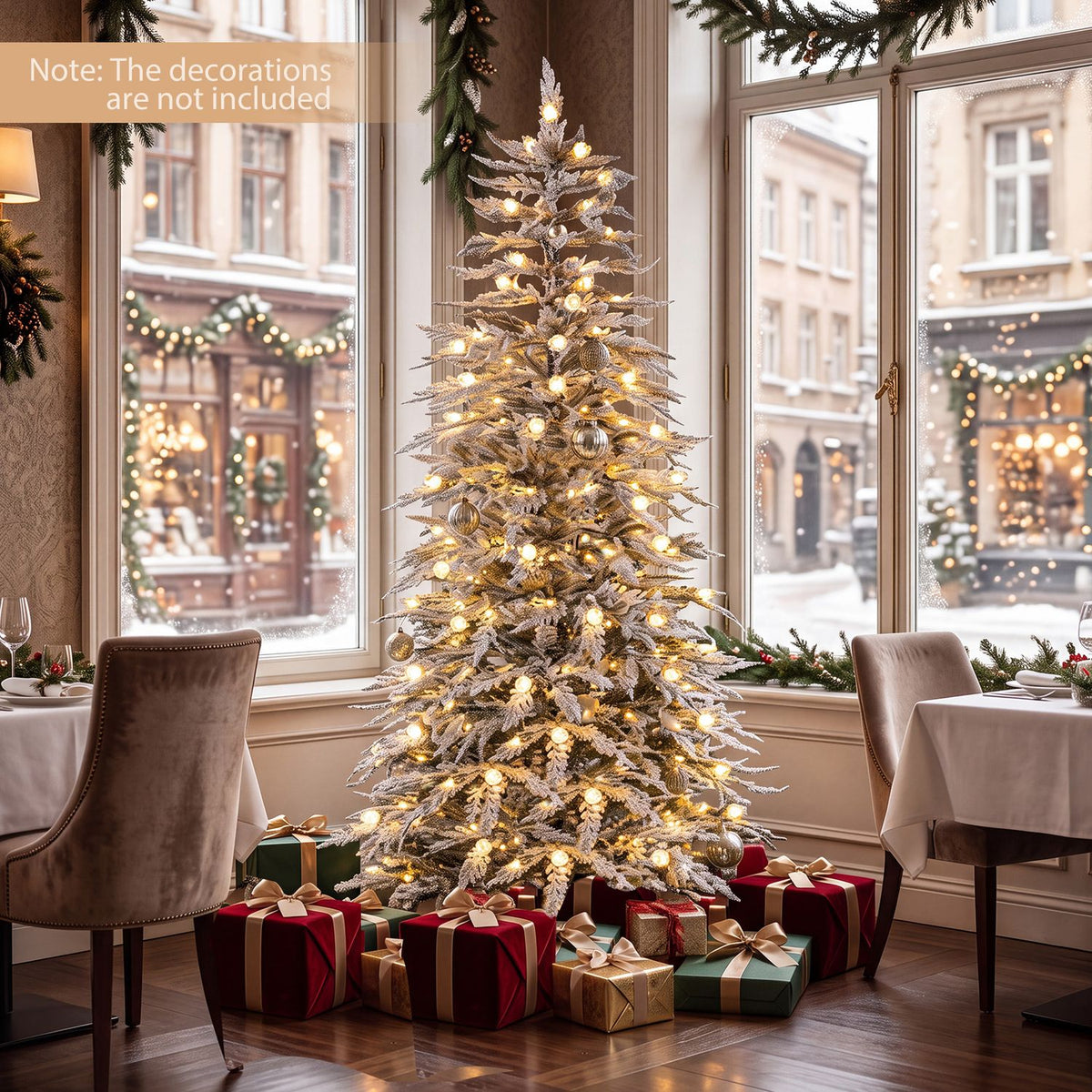 Warmly lit flocked Christmas tree displayed between chairs in a bright room