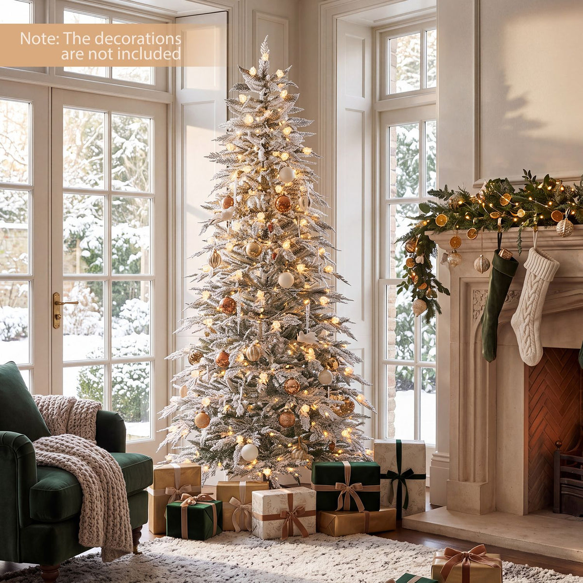 Warmly lit flocked Christmas tree with gold ornaments and presents beside a fireplace and green armchair.
