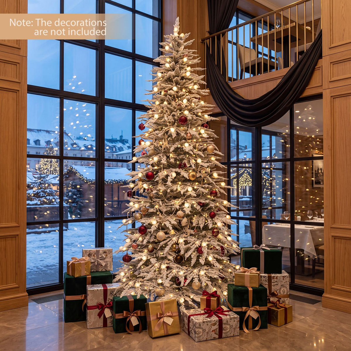 Snow-flocked Christmas tree glowing with warm lights and ornaments beside tall windows, with wrapped gifts at its base.