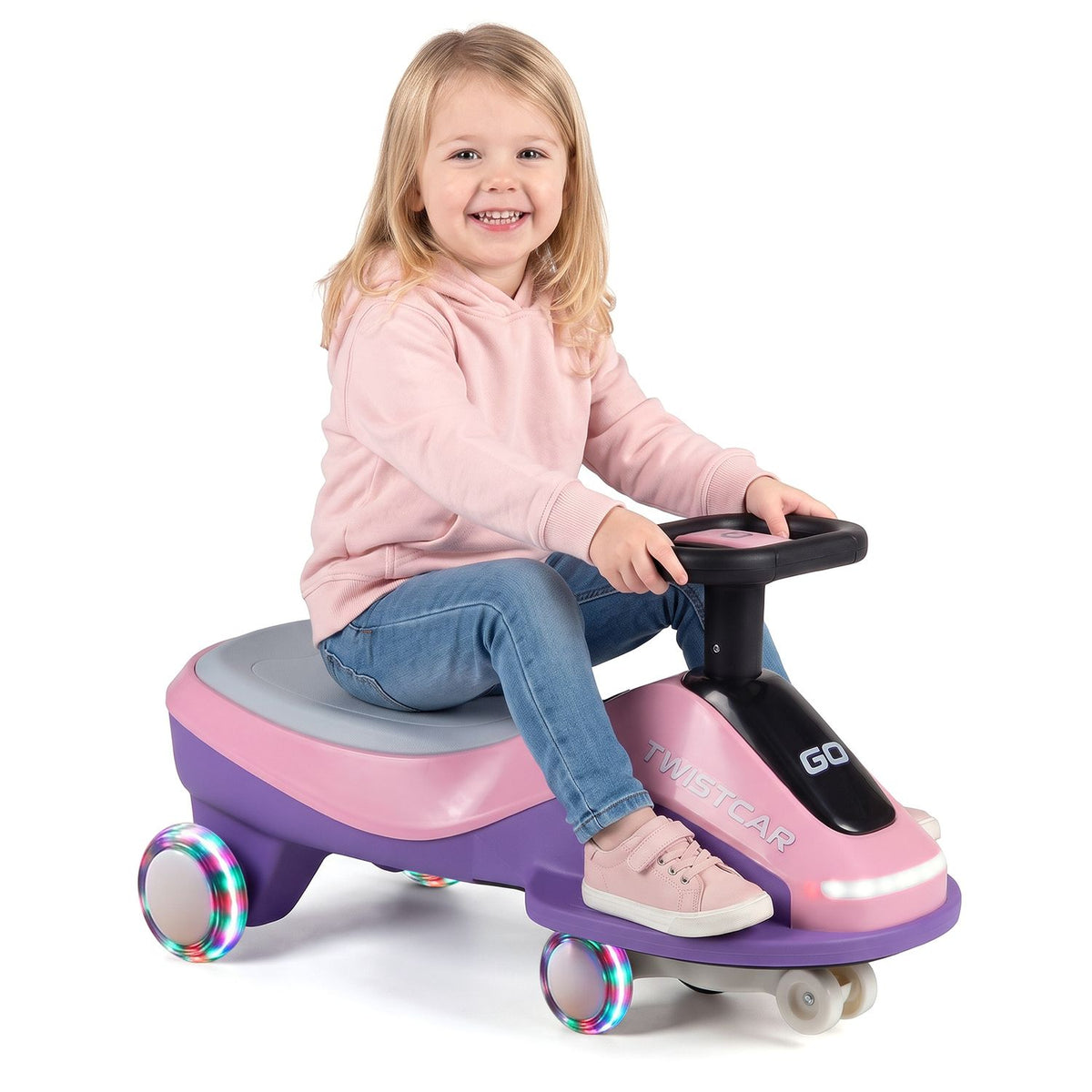 A child sits on the pink and purple ride-on car against a plain white background.