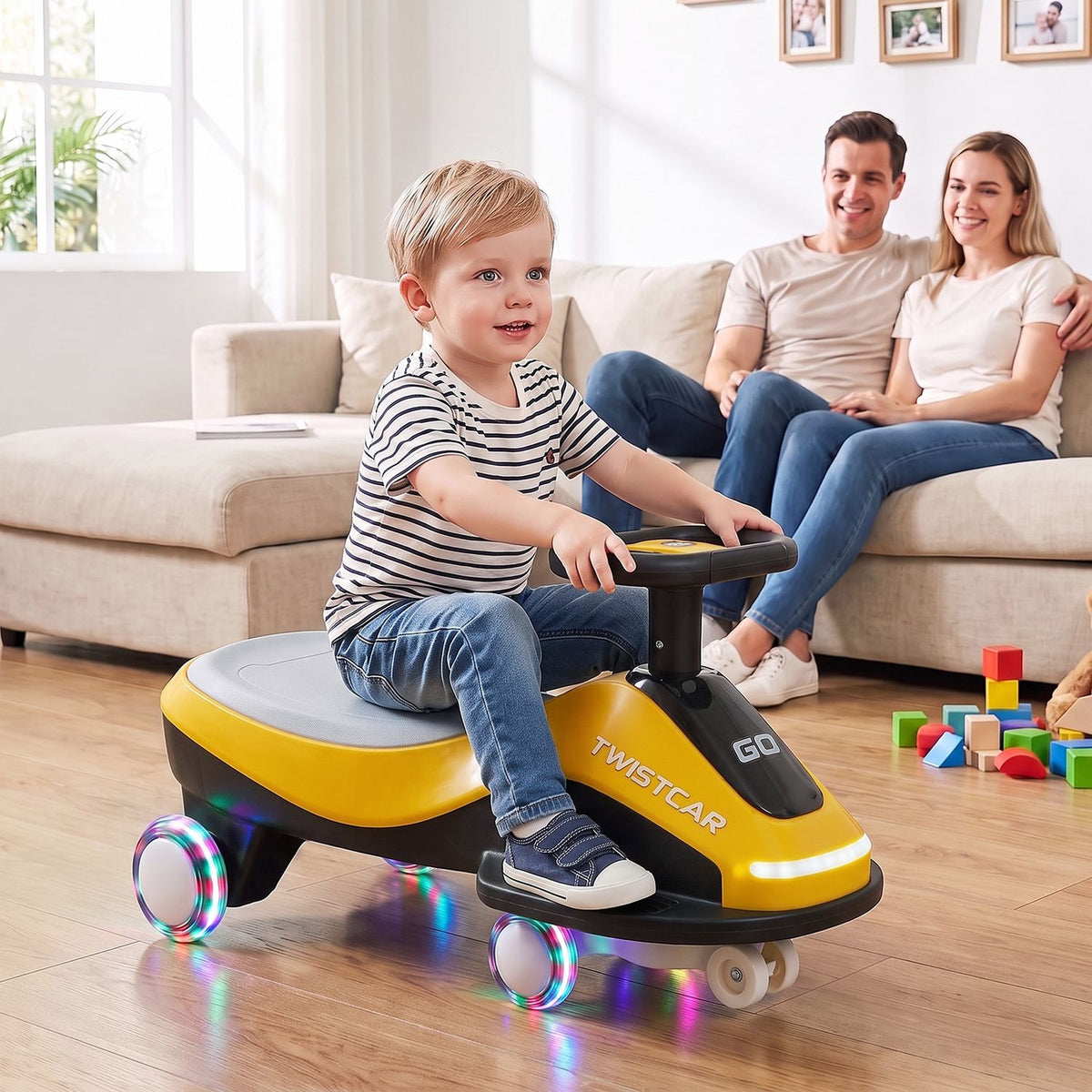 A child rides the yellow and black version of the toy car while two adults sit on a sofa behind him.