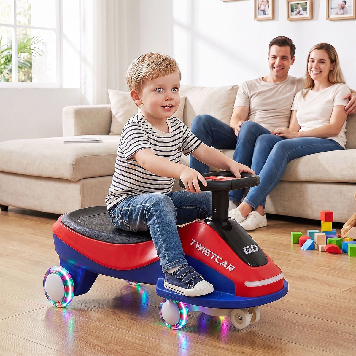 A child rides a red and blue version of the toy car in a living room as two adults watch from the sofa.