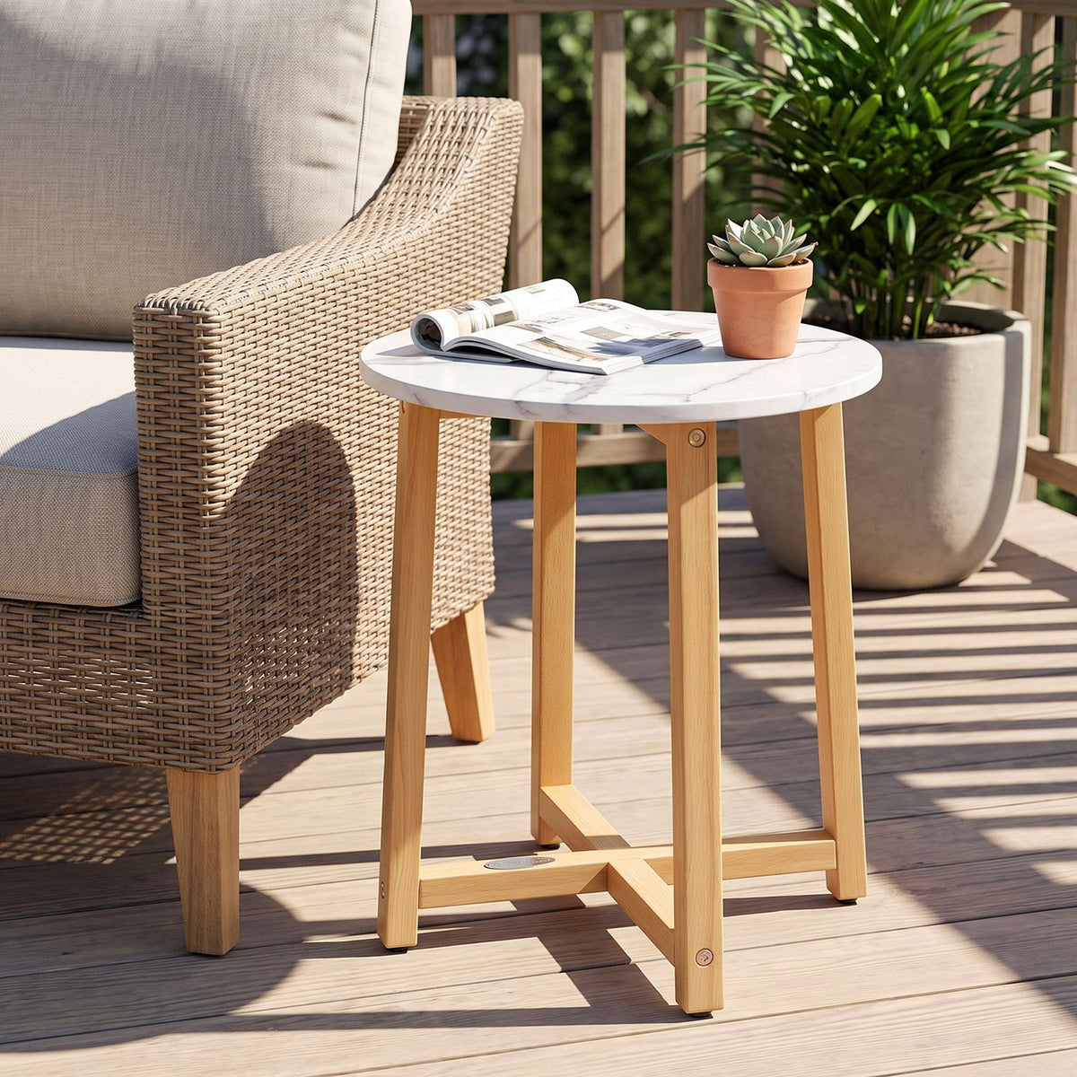 Round white faux-marble-look table with light wood legs beside a woven patio chair and potted plants.