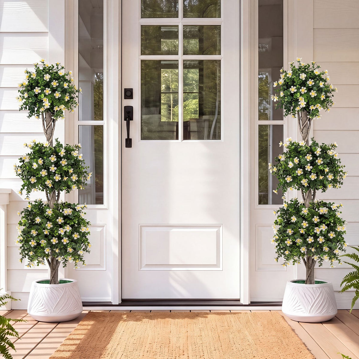 Pair of green topiary trees with white flowers in white pots beside a front door
