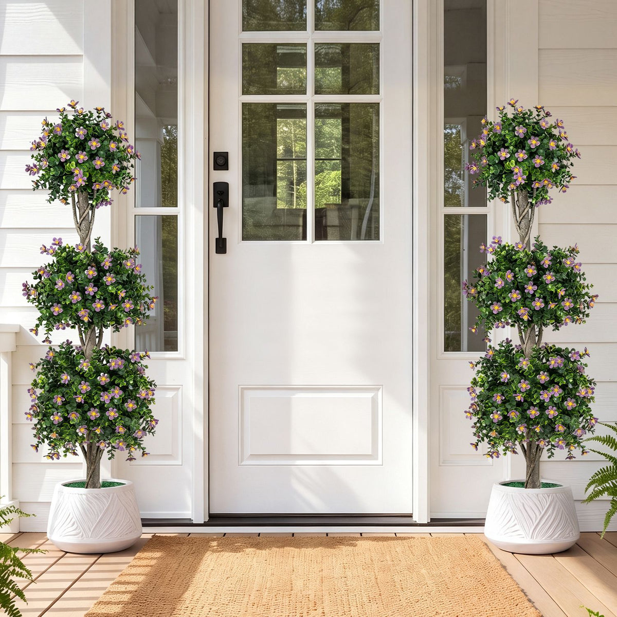 Two flowering topiary trees in white planters flank a home's front door.