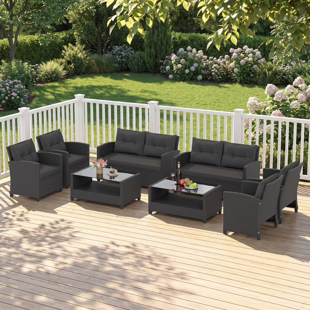 Black woven patio seating arranged around two glass-top coffee tables on a sunny deck.