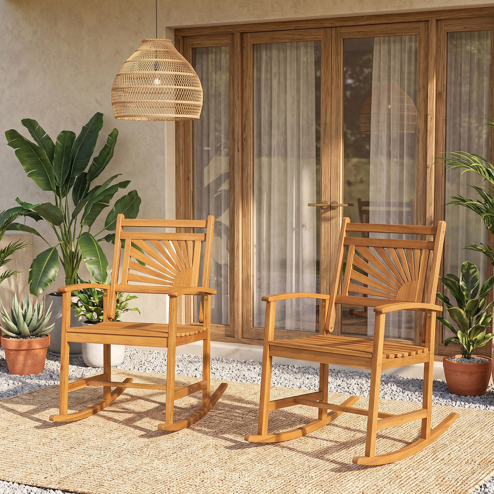 Two wooden rocking chairs on a woven rug in a covered patio with potted plants.