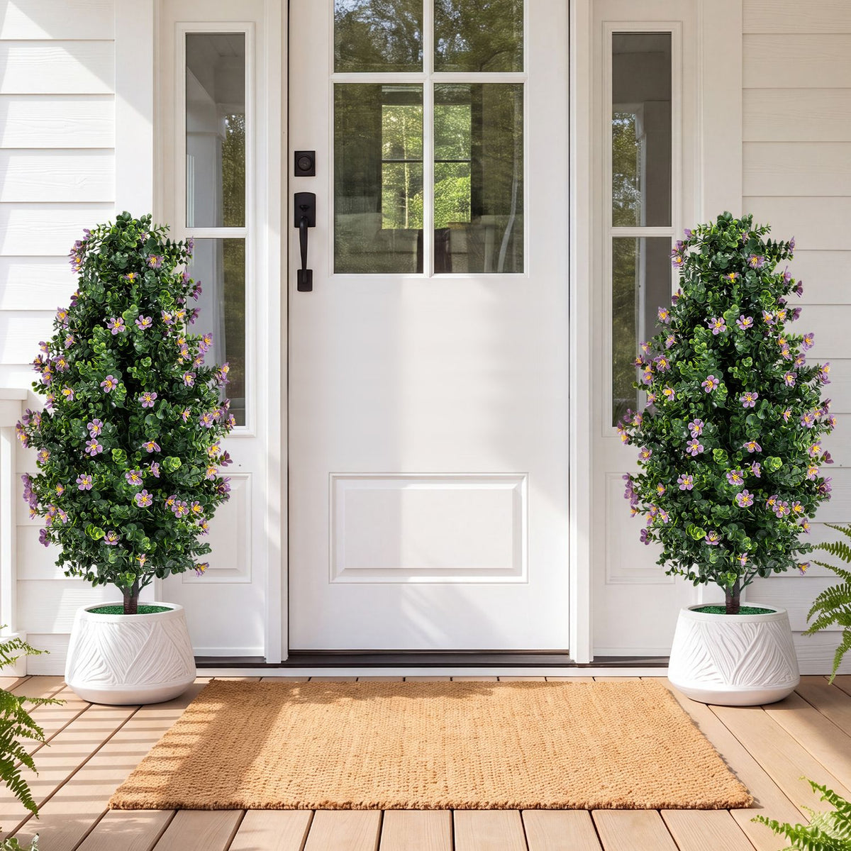 Two flowering topiary trees in white planters flank the front door.