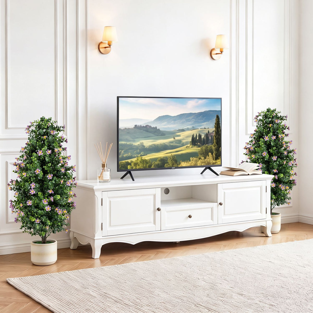 Two flowering topiaries stand beside a white media console in a bright living room.