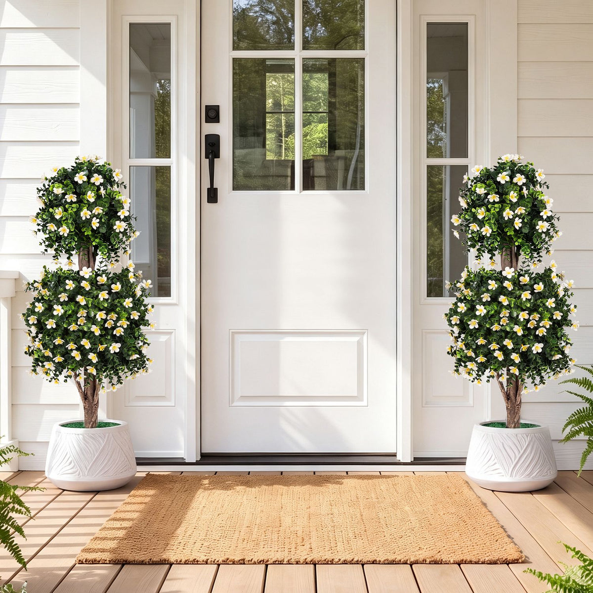 Two flowering topiary trees in white planters flank a front door on a porch.