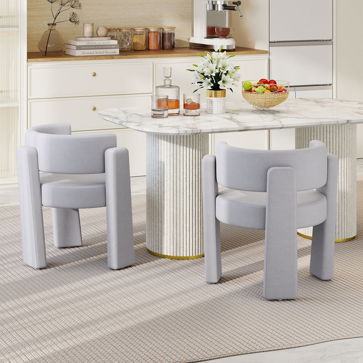 Two light gray barrel chairs beside a dining table in a bright room
