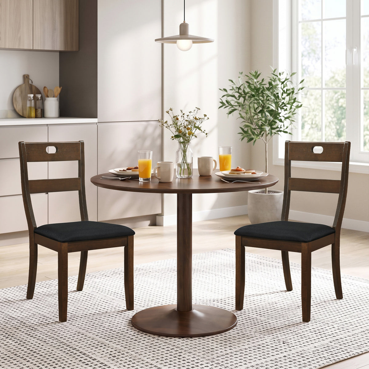 Pair of dark wood chairs with black seats arranged at a round dining table in a bright kitchen.
