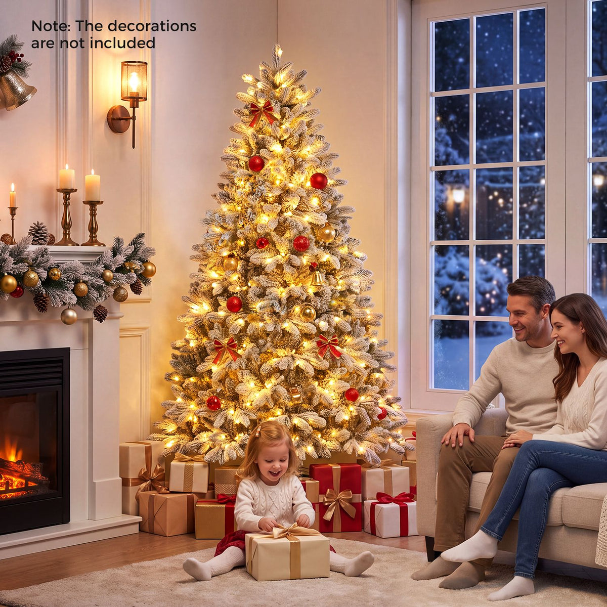 Decorated flocked tree glowing with warm lights as a child opens a gift beside two seated adults.