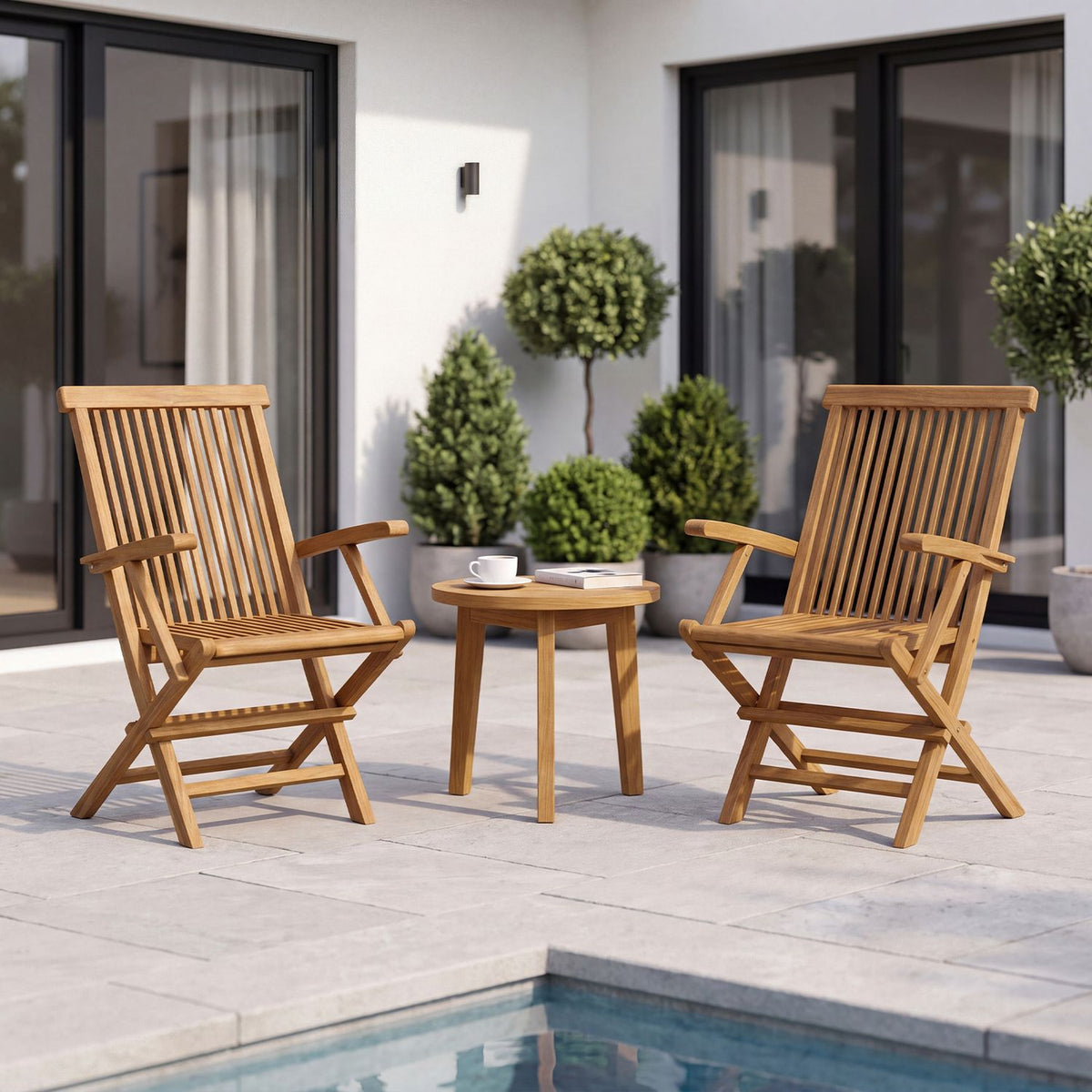 Pair of wooden folding armchairs arranged around a small table beside a swimming pool.