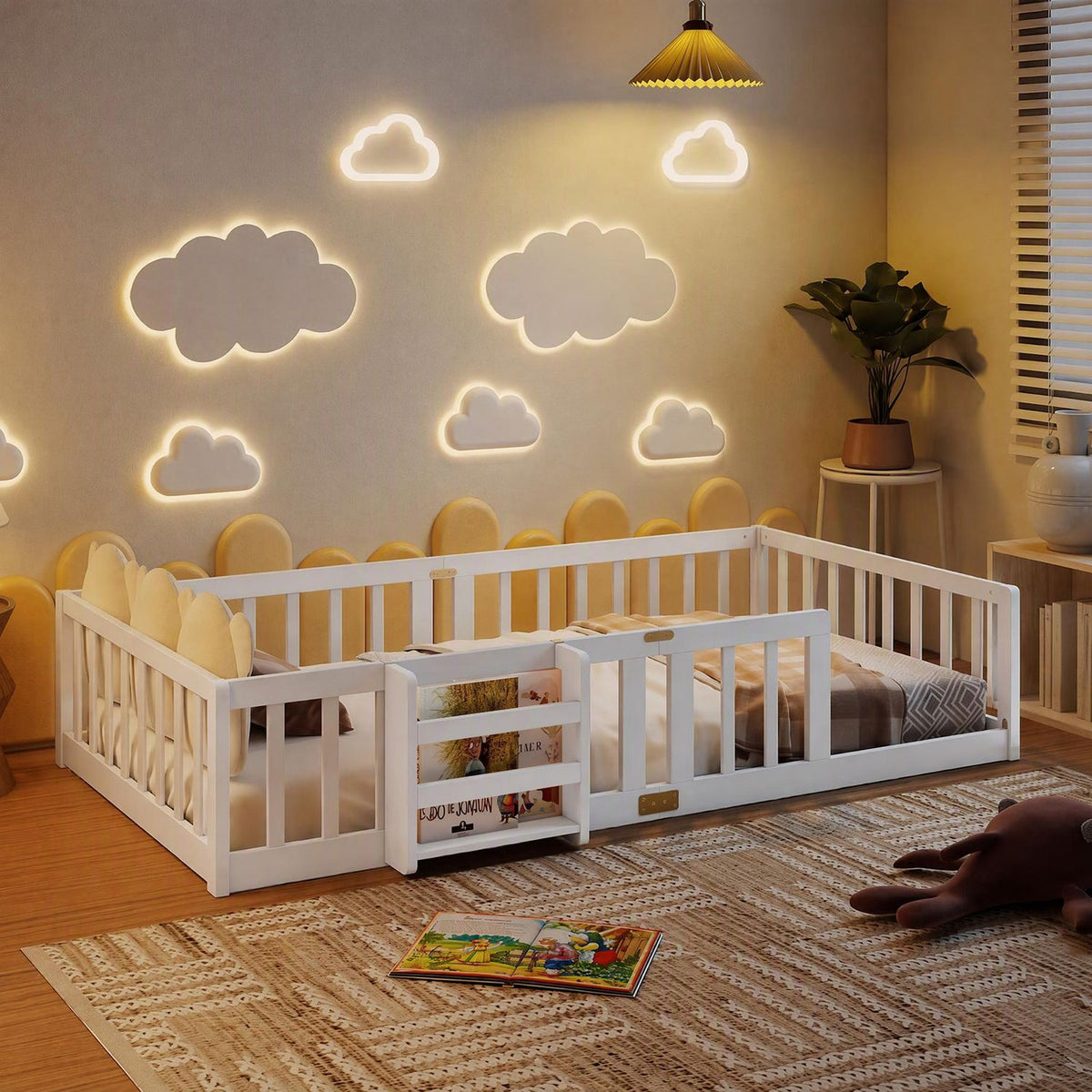 White low-profile bed enclosed by safety rails, styled with neutral bedding and a small bookshelf in a warmly lit room.