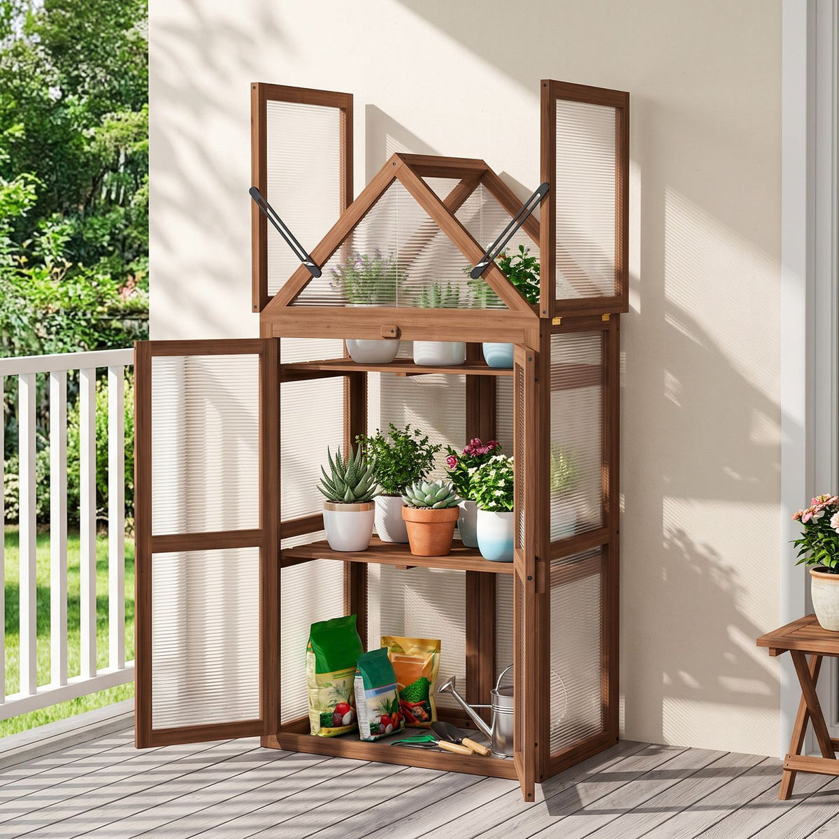 Open wooden greenhouse on a deck, displaying potted plants and gardening supplies on its shelves.