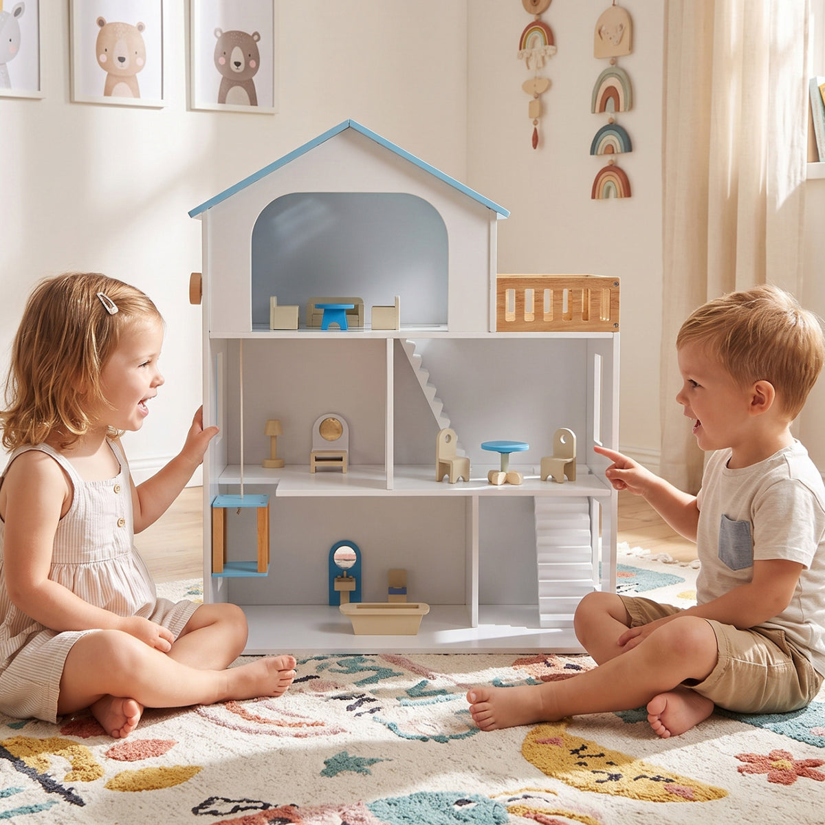 Two children sit facing an open dollhouse with miniature furniture arranged across its rooms.