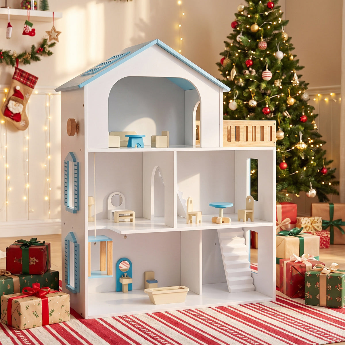 Furnished white dollhouse displayed on a striped rug beside a decorated Christmas tree and wrapped gifts.