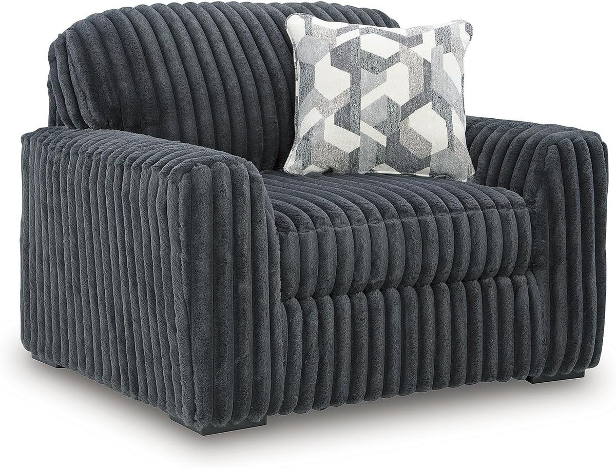 Close-up of a single oversized ribbed corduroy lounge chair with a geometric patterned throw pillow.