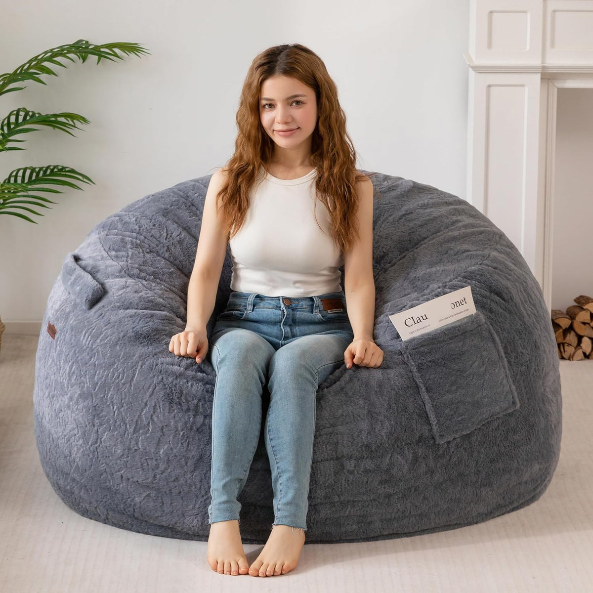 Front view of a woman sitting upright on a gray bean bag with a magazine in the side pocket.