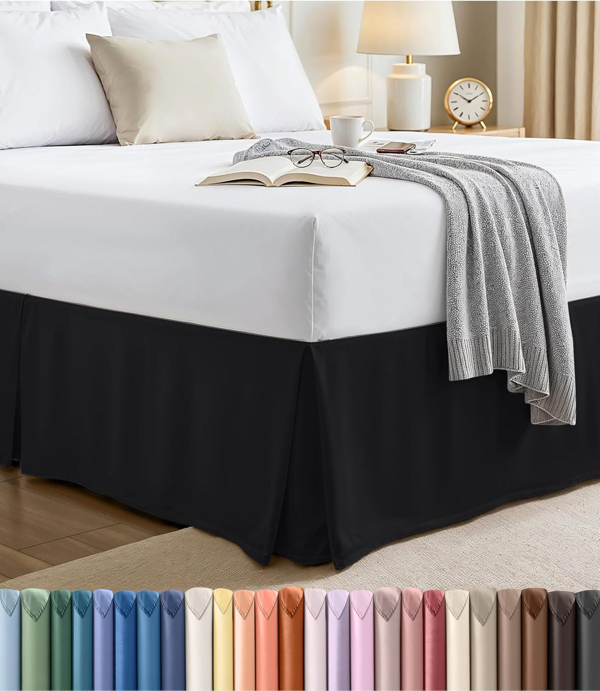 Bedroom corner showing a black pleated bed skirt under a white mattress with a cup and book on top