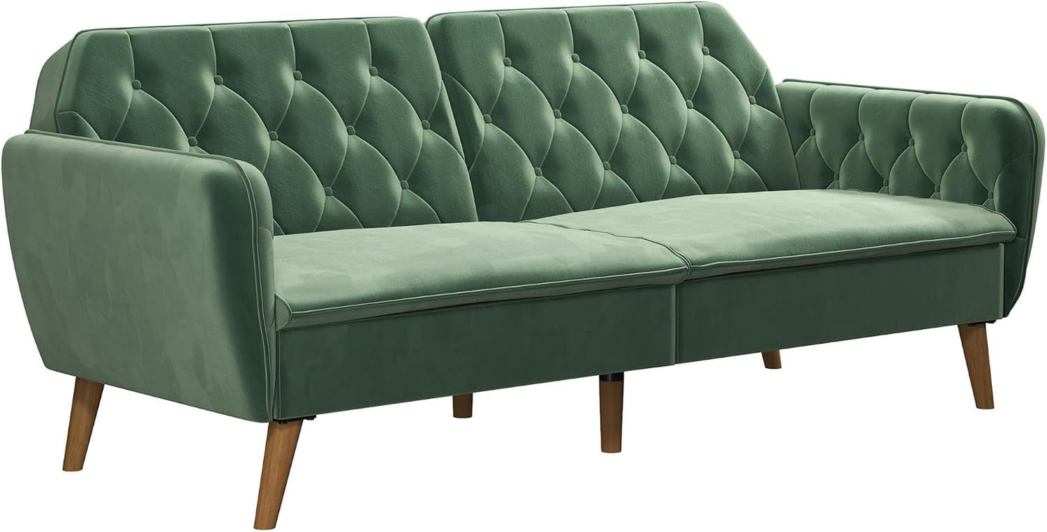 Side-angled studio view of the green velvet tufted futon sofa showing arm and leg detail