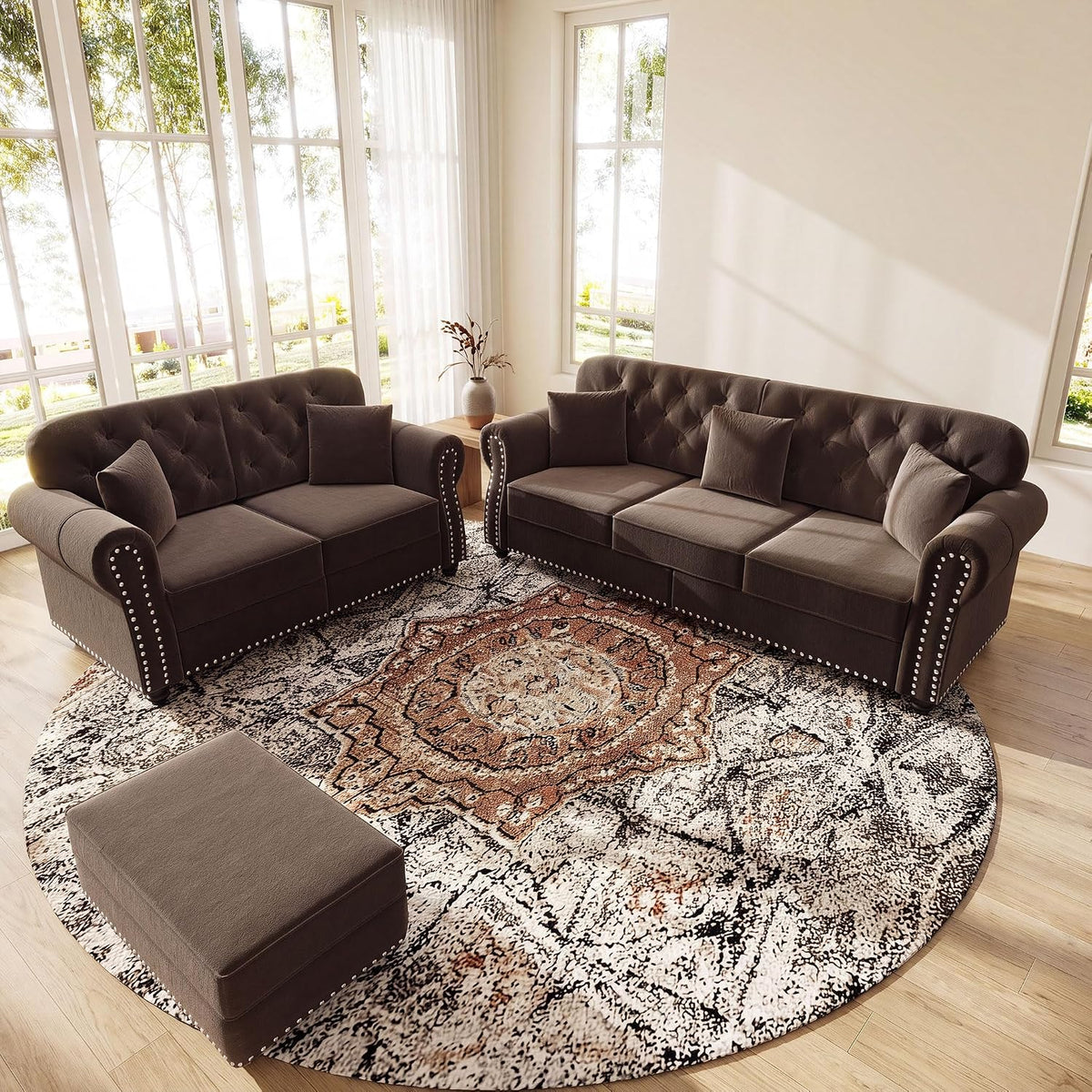 Brown velvet sofa and loveseat angled on a round patterned rug in a bright room with tall windows