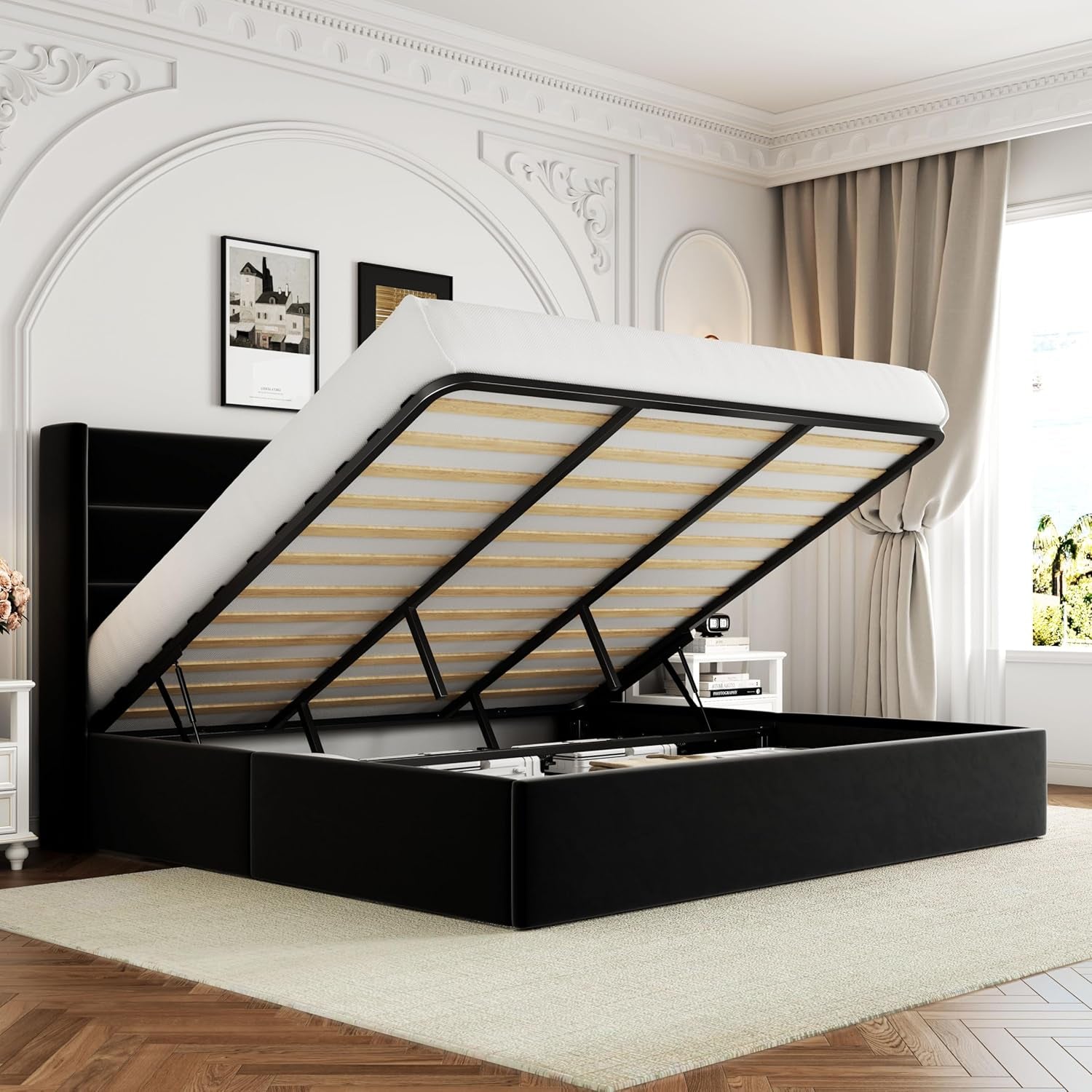 Black upholstered storage bed with gas-lift mattress raised to reveal deep storage, wingback headboard in a bright bedroom.