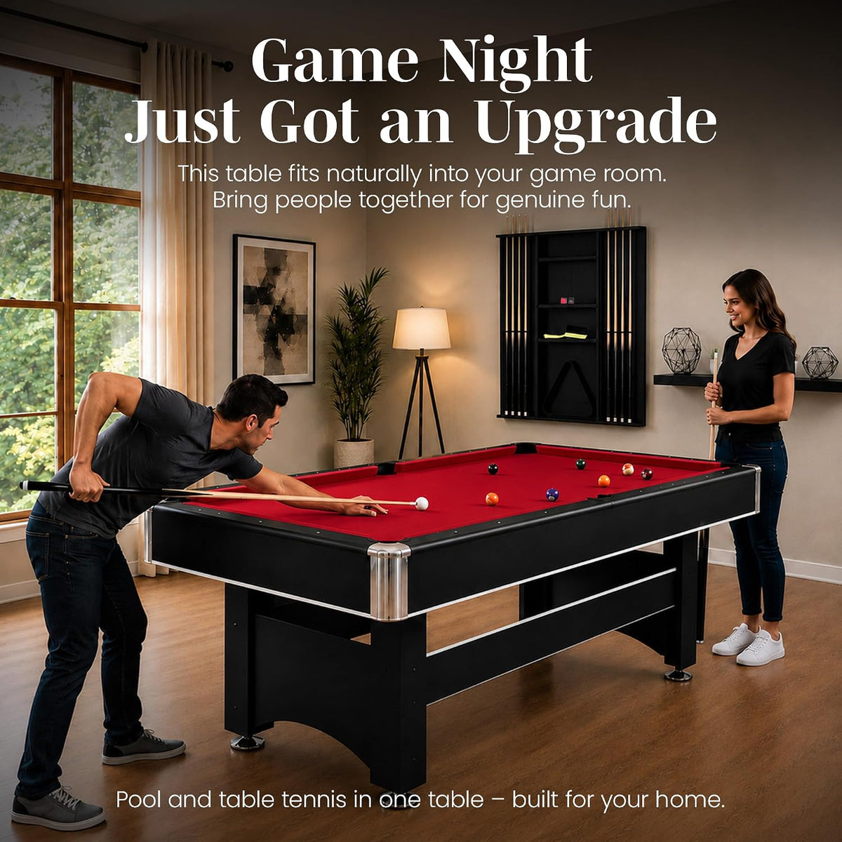 Two people enjoying a game at a red-felt pool table in a home game room, full-table view with wall rack visible