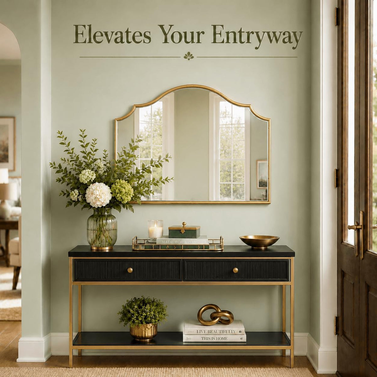 Gold scalloped arched mirror hung above a black and gold console table in an entryway, styled with flowers