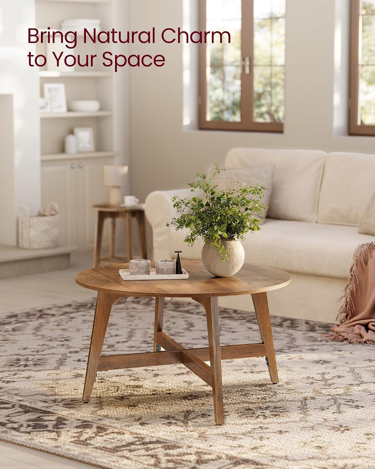 Honey-brown round coffee table styled in a bright living room on a patterned rug with sofa in background