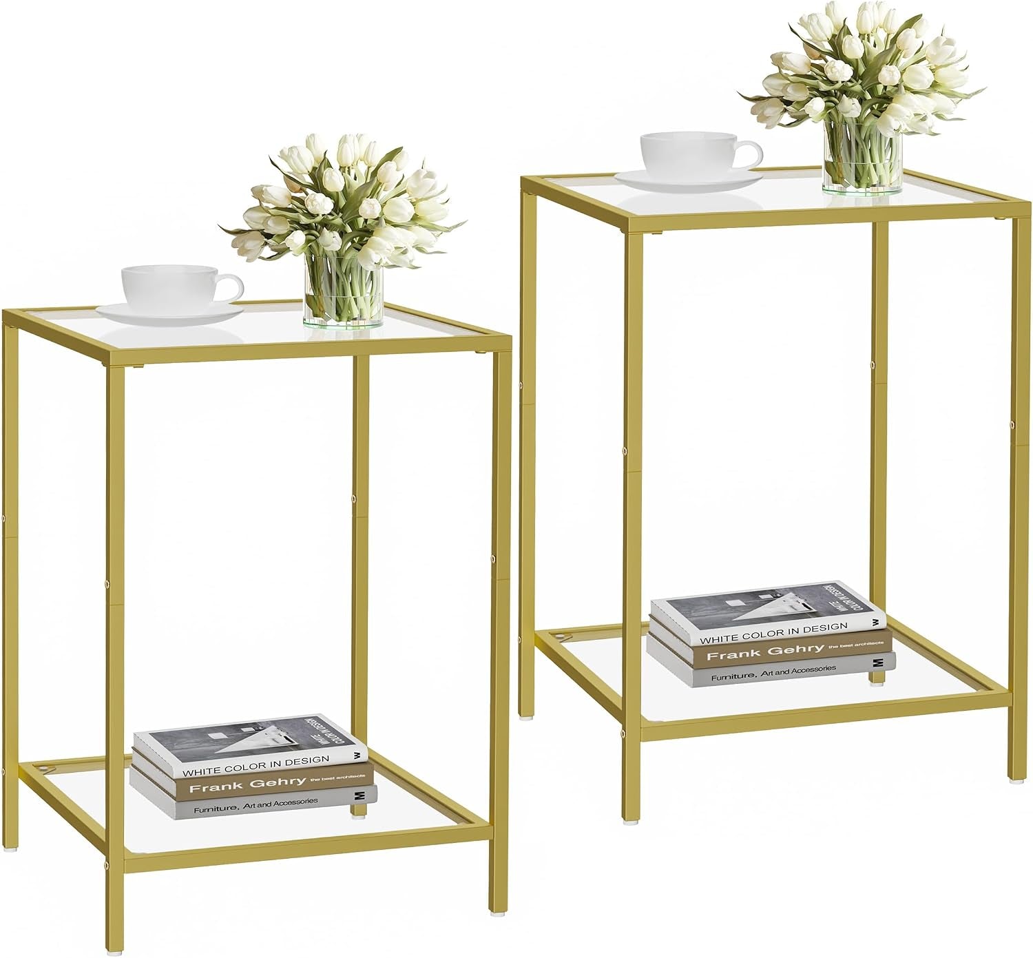 Two gold metal-framed side tables with white glass tops and lower shelves, staged with books, a cup, and a vase.