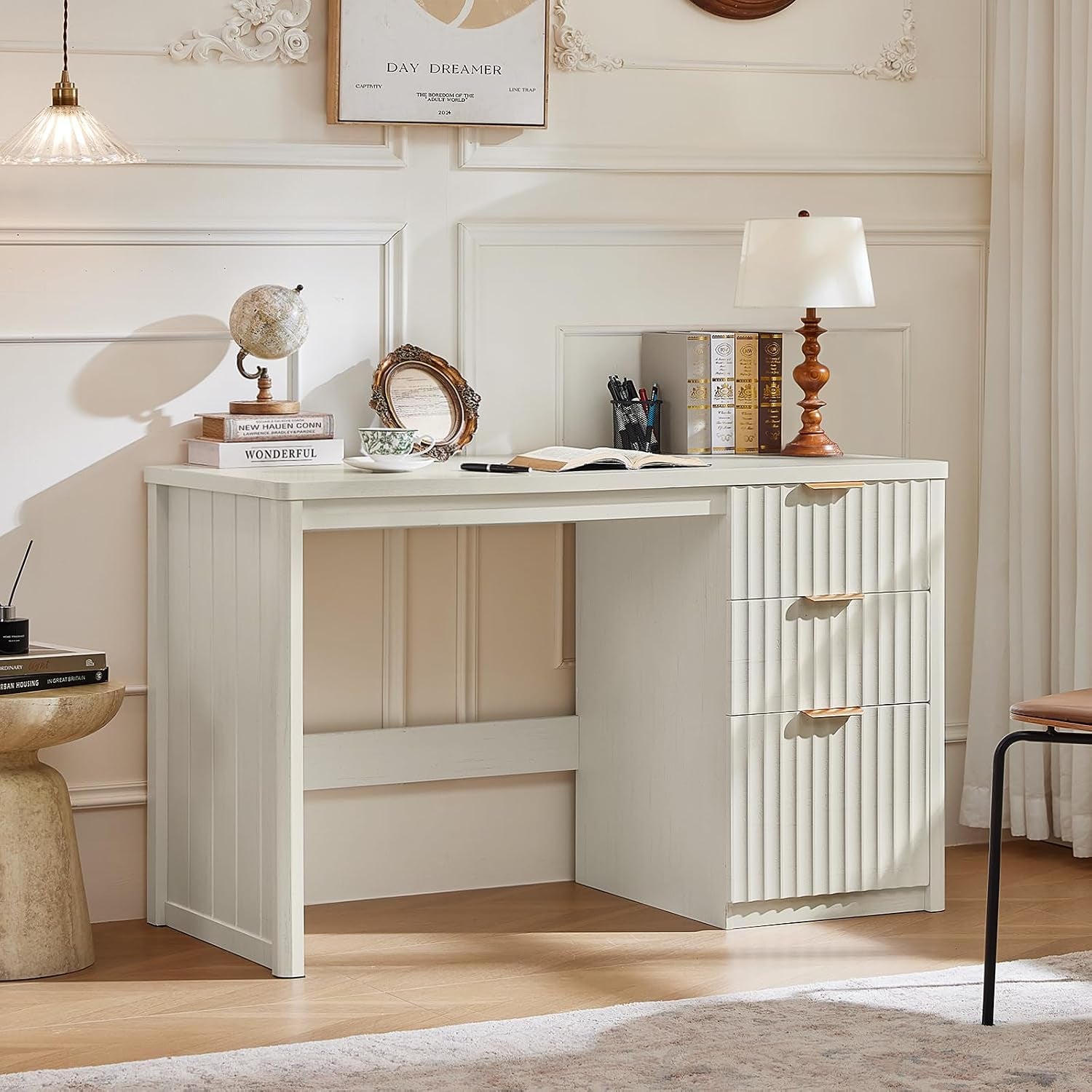 Off-white desk with three vertical fluted drawers, lamp and decorative items on the surface