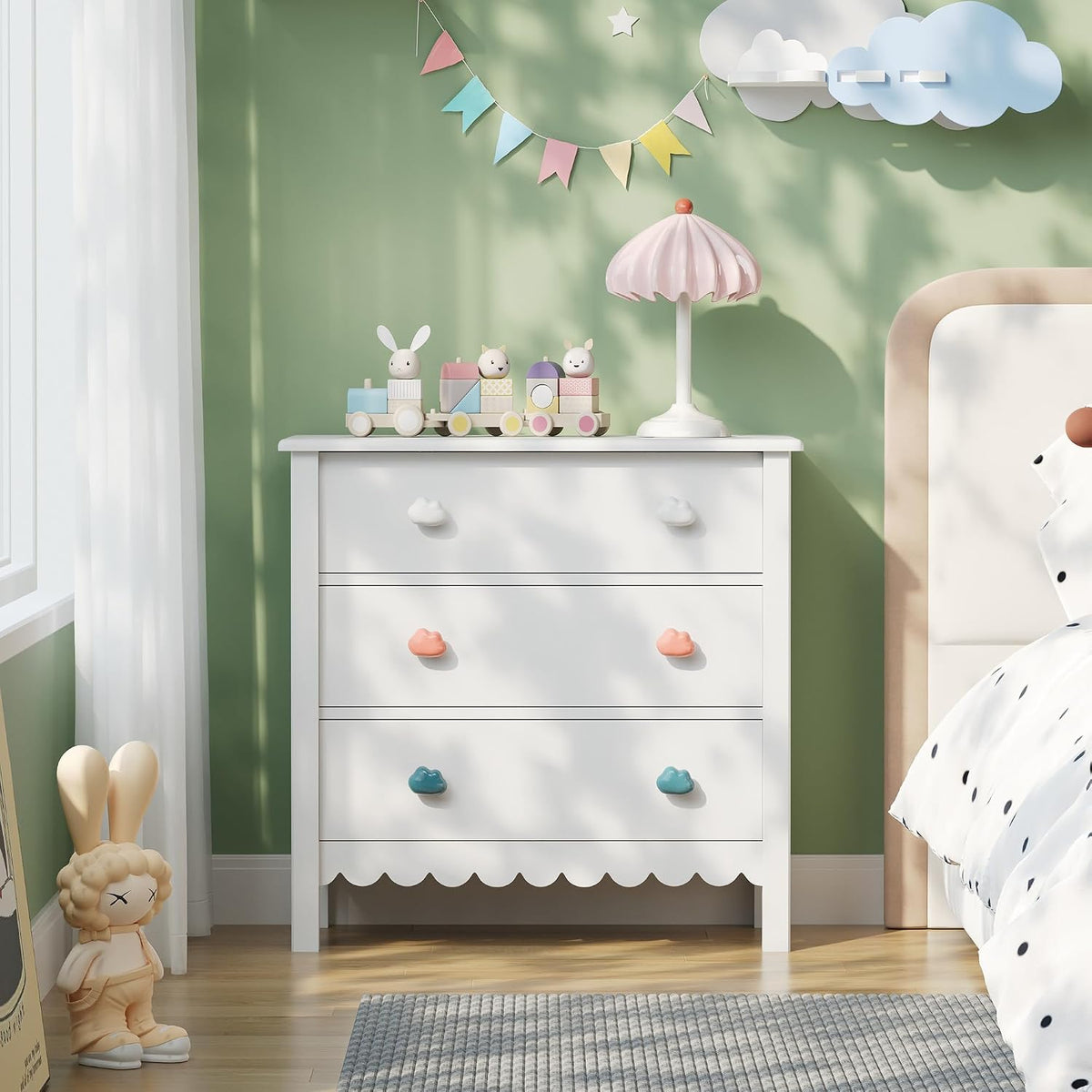 White scalloped dresser top view with lamp and wooden train against a green bedroom wall