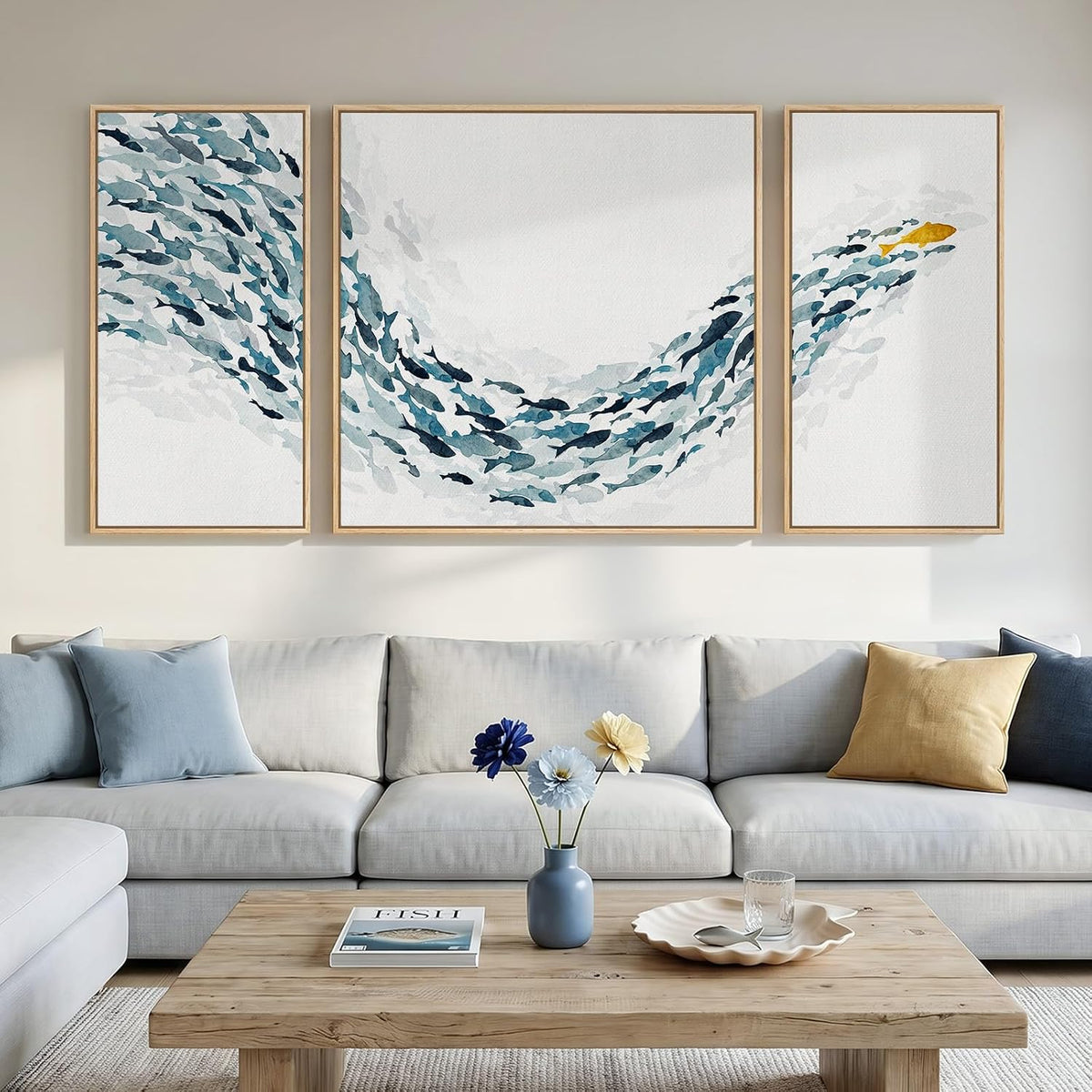 Three light-wood framed panels showing a school of blue fish forming a wave with one gold fish on the right.
