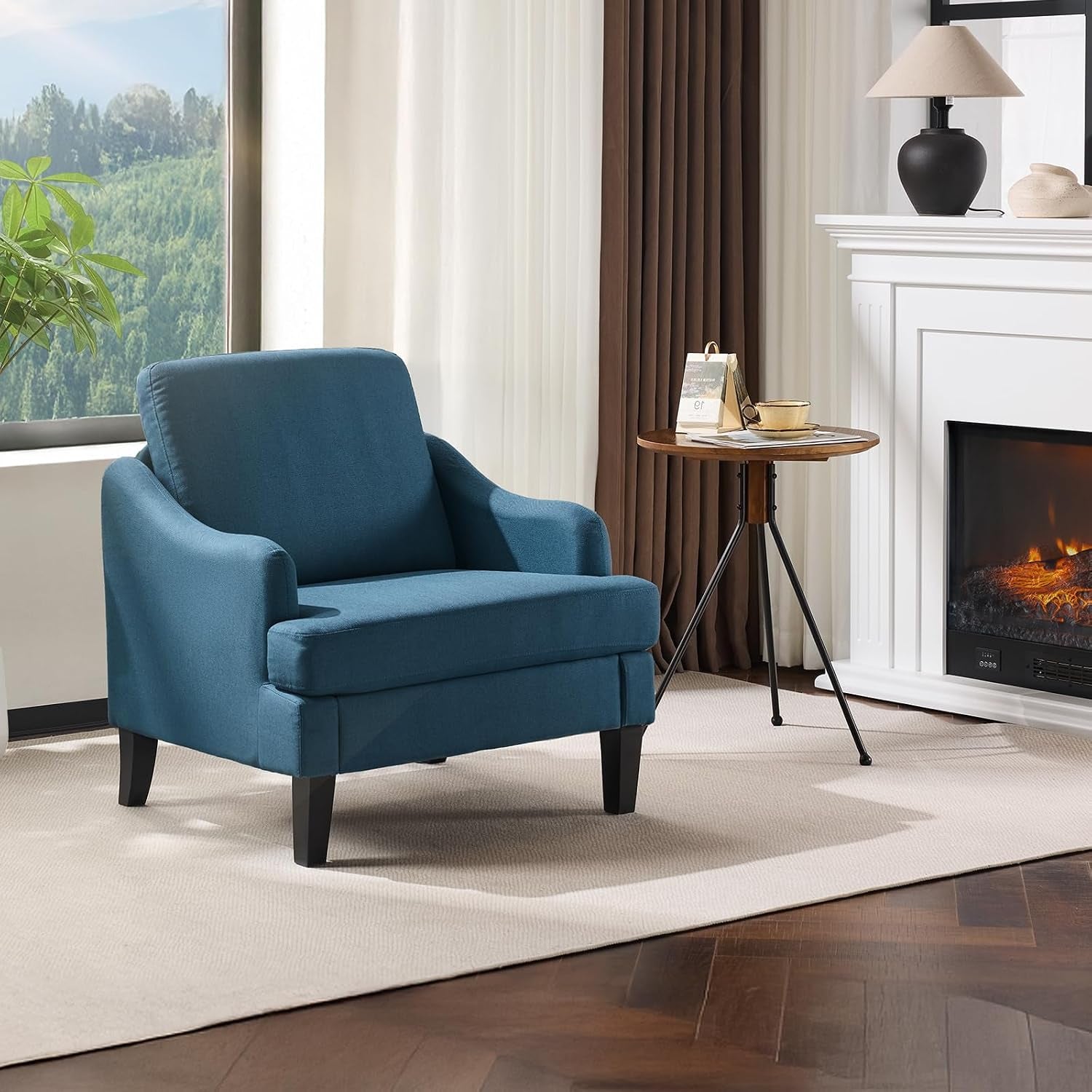 Single teal-blue upholstered armchair staged by a small round side table and fireplace.