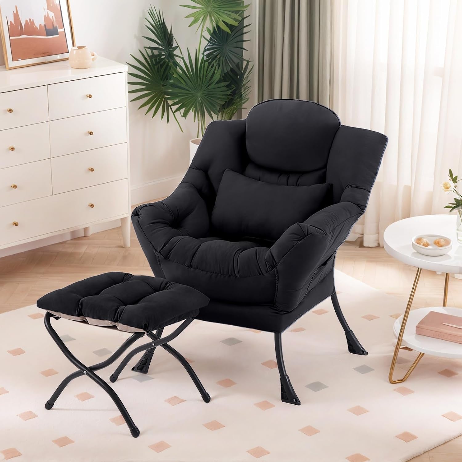 Black fabric accent lounge chair with matching ottoman and lumbar pillow staged in a softly lit room.